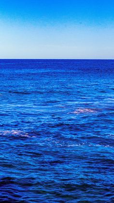 two people on surfboards in the middle of an ocean with blue sky and water