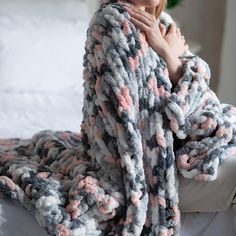 a woman laying on top of a bed covered in a blanket