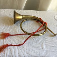 an old brass trumpet with red strings on a white bed sheet and linens in the background