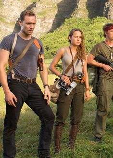 three people standing in the grass with camera equipment