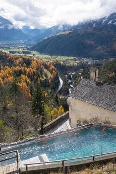 an outdoor swimming pool surrounded by mountains in the fall or early winter time with snow on the ground