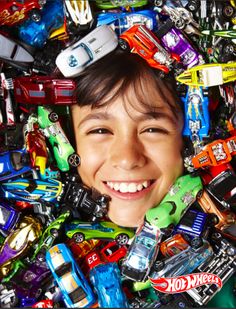 a young boy is surrounded by lots of toy cars