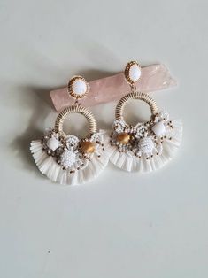 two pairs of earrings with tassels and beads on top of a white surface