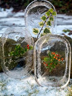 three glass vases with plants in them on snow covered ground