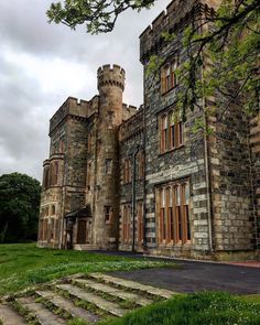 an old castle with stairs leading up to the front door and green grass on the ground