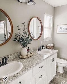 a bathroom with two sinks, mirrors and a toilet in the middle of the room