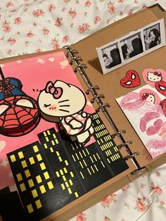 an open book with hello kitty and spiderman pictures on the cover, sitting on a bed