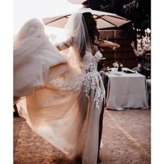 a woman in a wedding dress is dancing with an umbrella over her head and people sitting at tables behind her