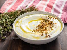 a white bowl filled with yogurt sitting on top of a wooden table next to a red and white towel