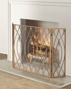 a fireplace with a fire in it on top of a hard wood floor next to a white wall