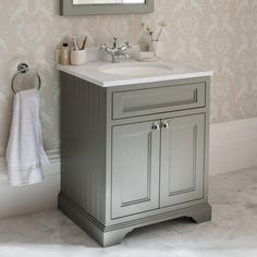 a bathroom with a sink, mirror and bathtub in it's corner next to a wallpapered wall