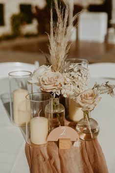 flowers and candles are arranged in vases on a table