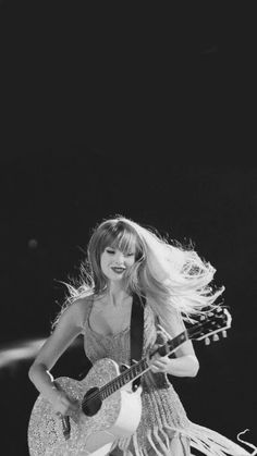 a black and white photo of a woman playing an acoustic guitar