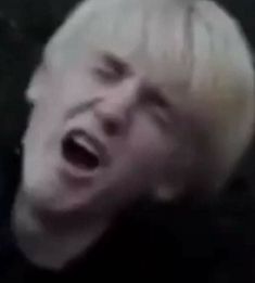 a man with blonde hair is screaming while wearing a black shirt and white wigs