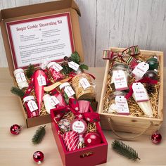 two boxes filled with christmas treats on top of a wooden table next to other items