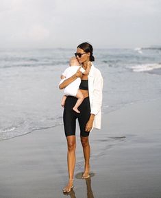 a woman holding a baby on the beach