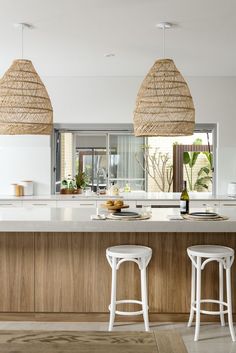 two white stools sit in front of an island