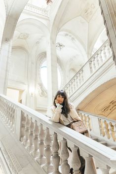 a woman sitting on top of a stair case next to a banister in a building