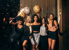 a group of women standing next to each other in front of balloons and confetti