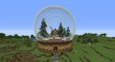 a large crystal ball sitting on top of a lush green field covered in snow and trees