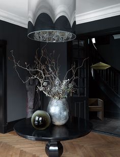 a vase with flowers on top of a table in front of a staircase and chandelier