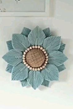 a wall hanging with a flower made out of yarn and wood beads on the side