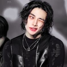 a man with black hair and piercings wearing a leather jacket is looking at the camera