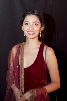 a woman in a red dress smiling at the camera with her hand on her hip