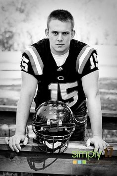 a black and white photo of a football player leaning on a rail with his helmet