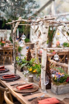 the table is set with place settings and flowers in glass vases, which are hanging from branches