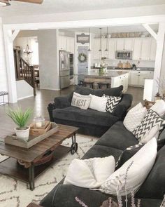 a living room filled with black couches and white pillows