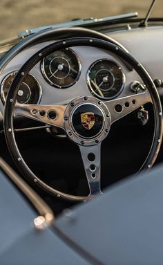 the steering wheel and dashboard of an old classic sports car with chrome spokes,