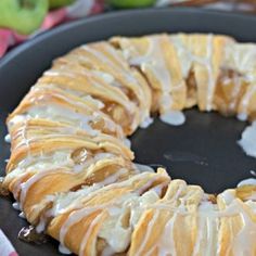 a bundt cake with icing and apples in the background on a black plate