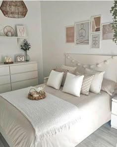 a bedroom with white furniture and pictures on the wall above the bed, along with a wicker basket