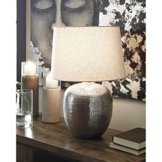 a lamp sitting on top of a wooden table next to a book and glass vase