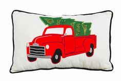 a red truck with a christmas tree on it's back is sitting in front of a white pillow