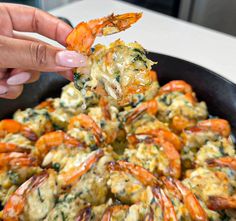 a person dipping some food into a skillet with shrimp and spinach on it