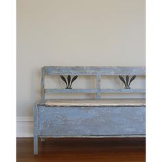 an old blue bench with two black birds on it's backrests in front of a white wall