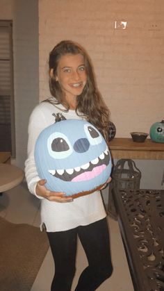 a woman is holding a blue pumpkin shaped like a monster with big teeth on it's face