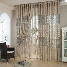 a living room filled with furniture and windows covered in sheer curtain panels, along with a rug on the floor