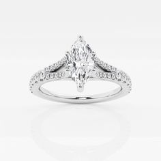 a white gold ring with a pear shaped diamond in the center and pave set shoulders