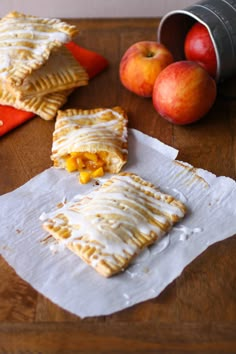 two pieces of pie on top of paper next to apples and a cannister