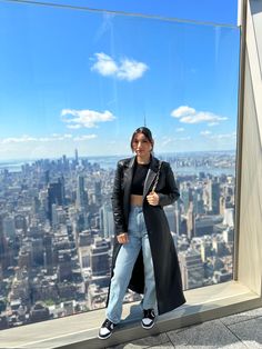 a woman standing on top of a tall building in front of a cityscape