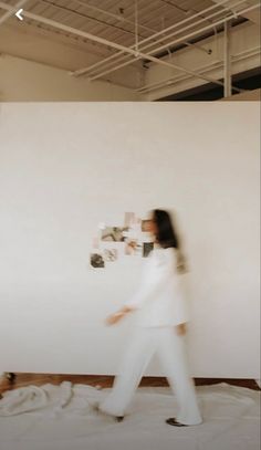 a blurry photo of a woman walking in front of a white wall