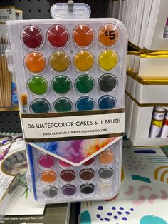 an assortment of watercolor cakes and brush in a plastic case on display at a store