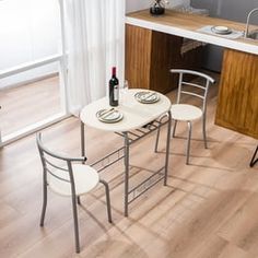 a small kitchen table with chairs and a wine bottle on the counter next to it