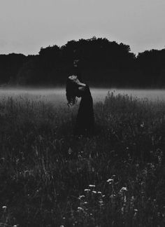 black and white photograph of two people standing in the middle of a foggy field