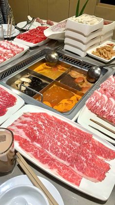 various meats are displayed on trays at a buffet