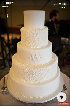 a three tiered white wedding cake sitting on top of a table next to a knife and fork