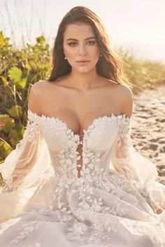 a woman in a wedding dress sitting on the beach